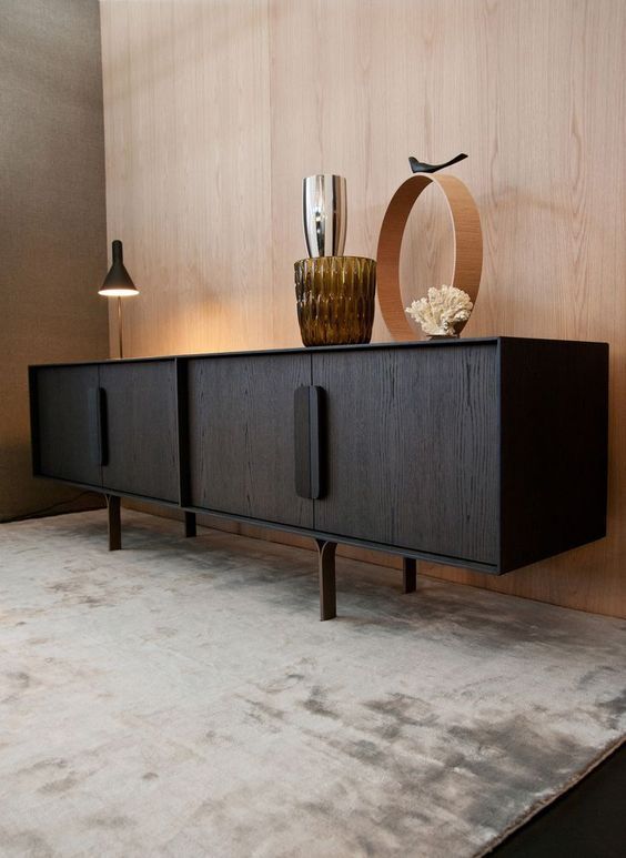 a black cabinet with two vases on top of it next to a white rug