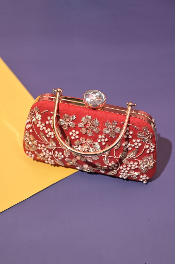 Styles like an enigma with the new red color designer clutch bag with heavy zari embroidery work and a metal handle. You can use it as a clutch, handbag also a sling. It comes with a big shoulder strap in metal. It has one main compartment with a click closure and a metal bolt. Carry this bag this festive season and look glamorous. Color: ﻿Red Material: Silk Size: 8 inch X 5 inch Care: Wipe with a dry cloth Red Clutch With Zari Work, Festive Red Embroidered Clutch, Rectangular Red Clutch With Handwork, Red Embroidered Leather Bag, Traditional Red Embroidered Clutch, Designer Clutch Bags, Big Shoulders, Designer Clutch, Lint Roller