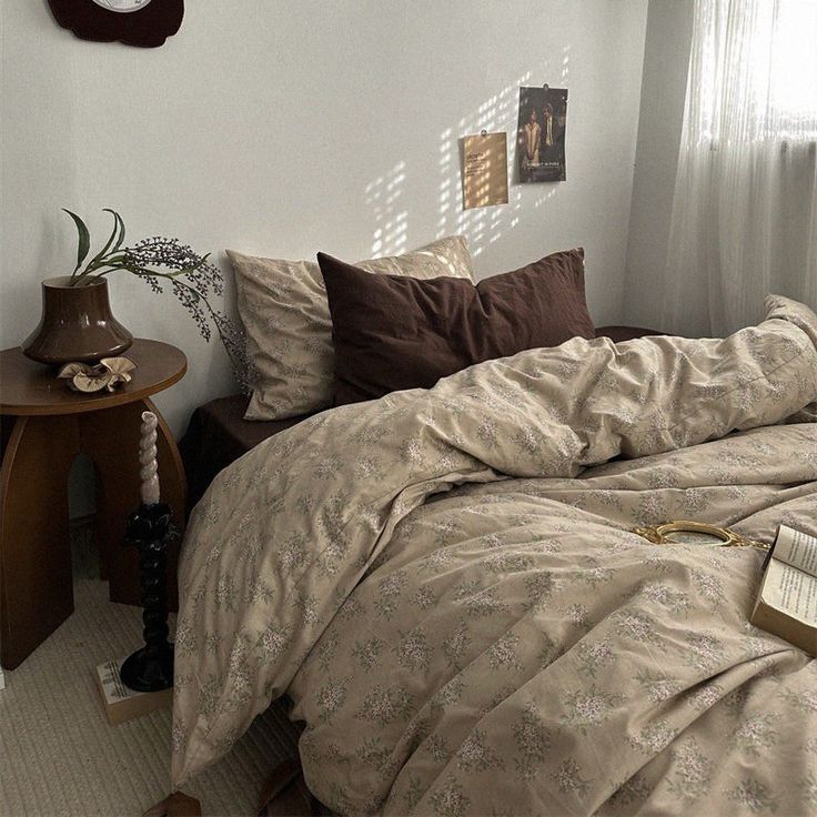 a bed sitting in a bedroom next to a wooden table with a clock on it