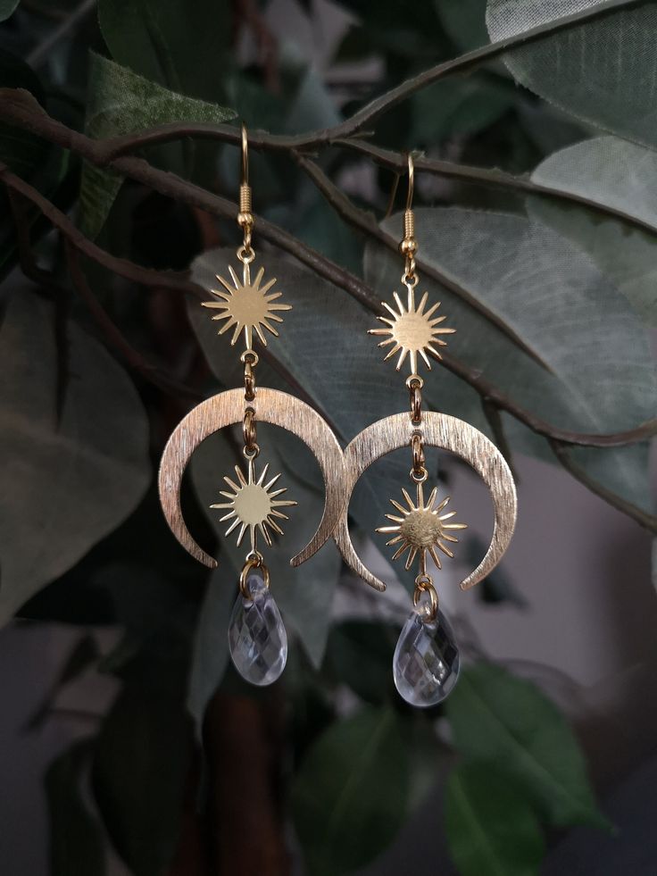 These gold-colored witchy sun and moon earrings are handmade in Finland. The hooks are made of 18K gold-plated surgical stainless steel so they are suitable for sensitive skin. The sun and moon pendants are chrome and the clear drop bead is acrylic. Moon Goddess Jewelry, Sun Moon Earrings, Sun And Moon Earrings, Aesthetic Jewellery, The Sun And Moon, Earrings Moon, Celestial Earrings, Goddess Jewelry, Princess Core