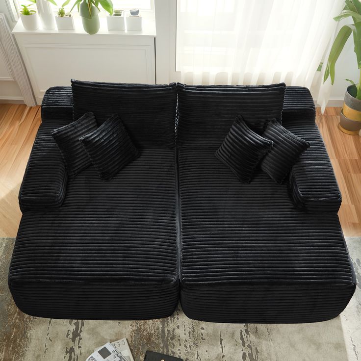 a large black couch with two pillows on it's sides and a magazine next to it