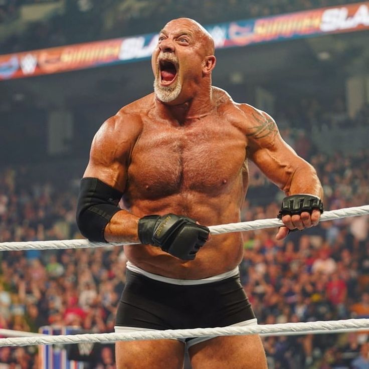 the wrestler is screaming while standing in front of an audience with his hands on ropes