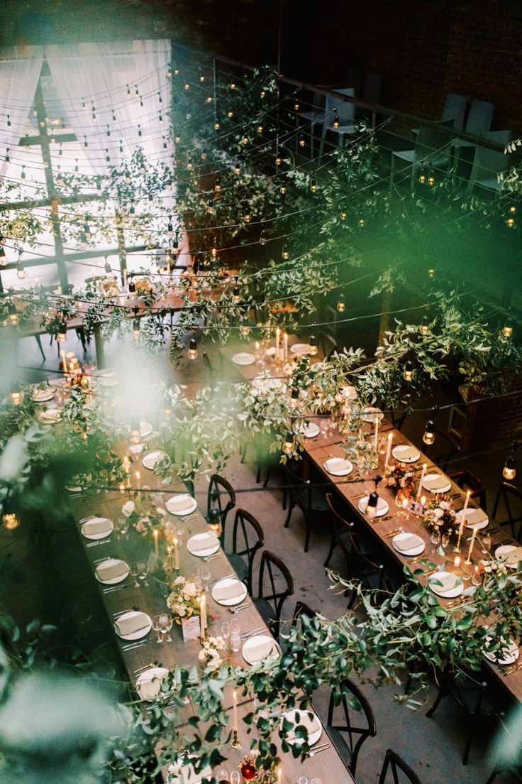 an overhead view of a long table with candles and greenery in the center surrounded by other tables