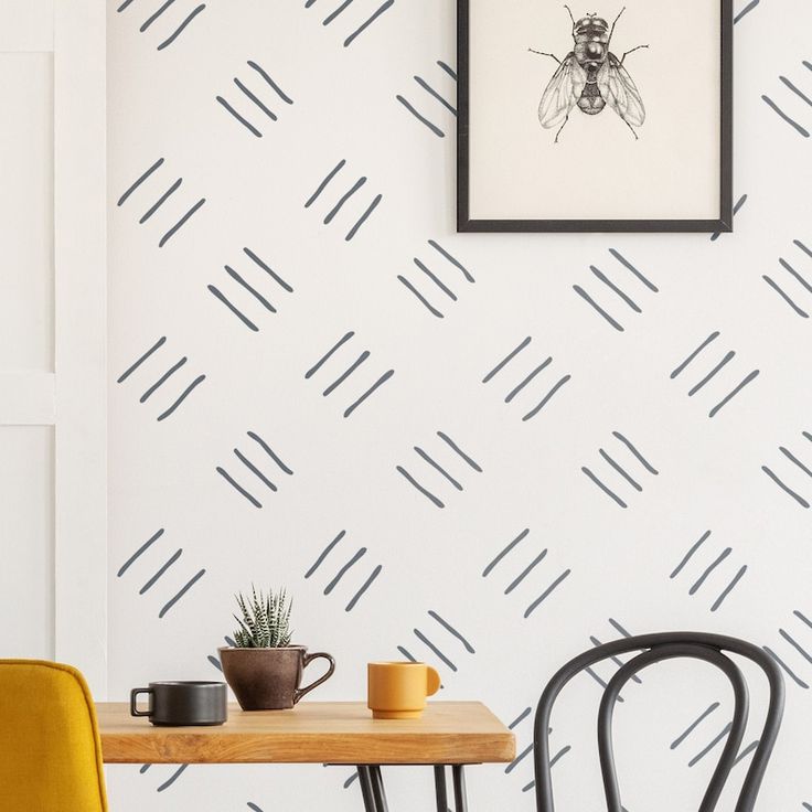 two chairs and a table in front of a white wall with black lines on it