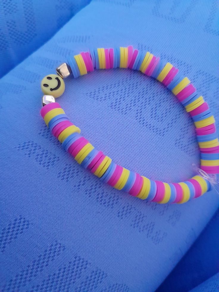 a colorful bracelet with a smiley face on it's end and two small beads attached to the clasp