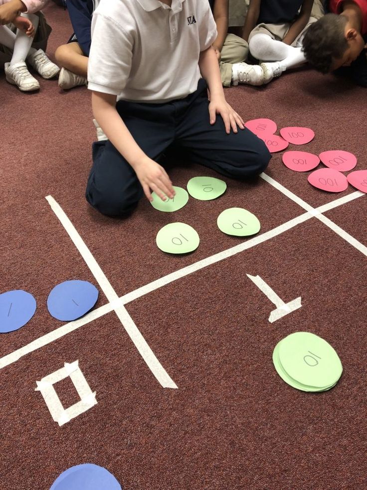 a group of children sitting on the floor playing with paper circles and numbers in front of them