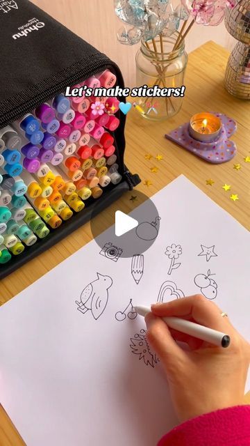 a person is drawing with crayons on a piece of paper next to a box of markers