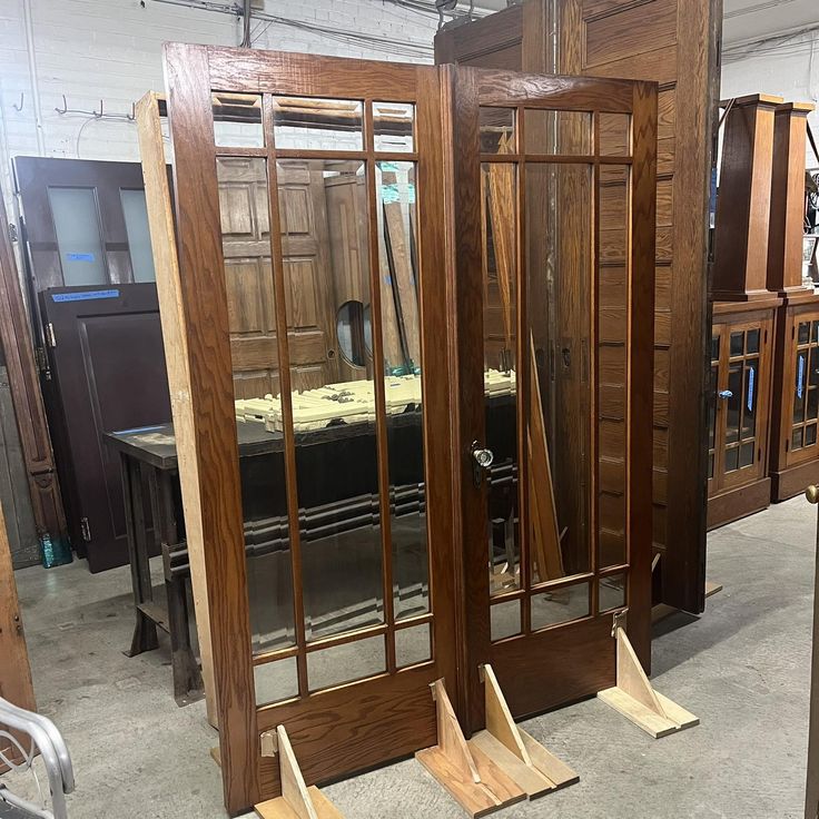 three wooden doors with mirrors on them in a room filled with furniture and other items