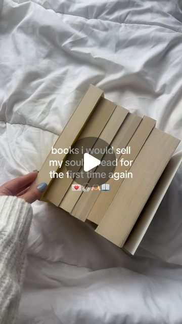 someone is holding a book in their hand on a bed with white sheets and pillows