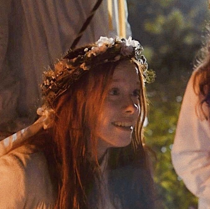 a woman with red hair wearing a flower crown