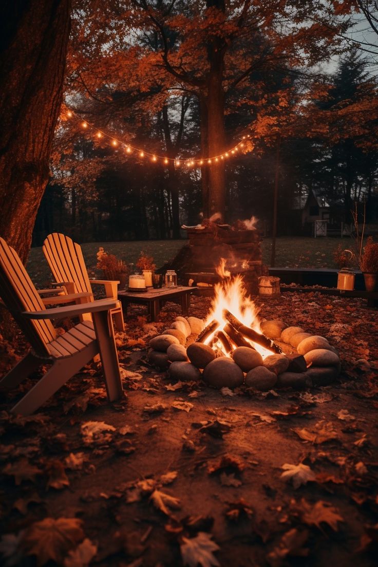 an outdoor fire pit with chairs around it and string lights strung over the trees in the background