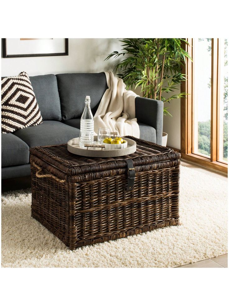 a wicker coffee table sitting on top of a rug in front of a couch