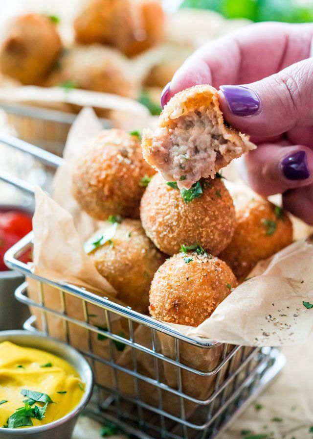 a person holding a meatball in their hand and dipping sauce on the other side