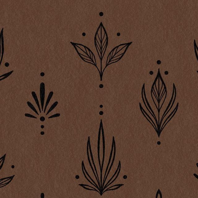 a brown paper with black leaves and dots on the bottom half is shown in this image