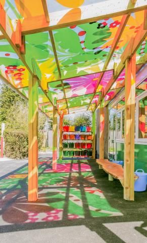 an outdoor covered area with benches and colorful decorations on the roof, along with potted plants