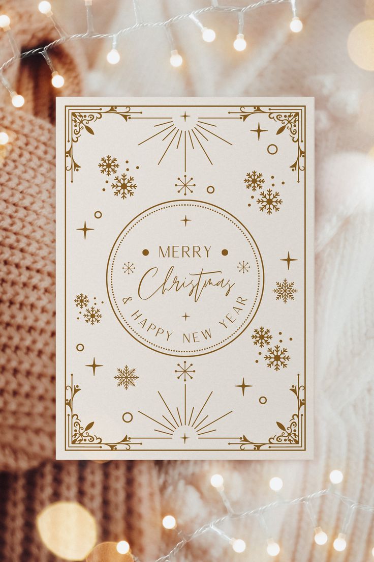 a white christmas card with gold foil and snowflakes on the front, surrounded by lights