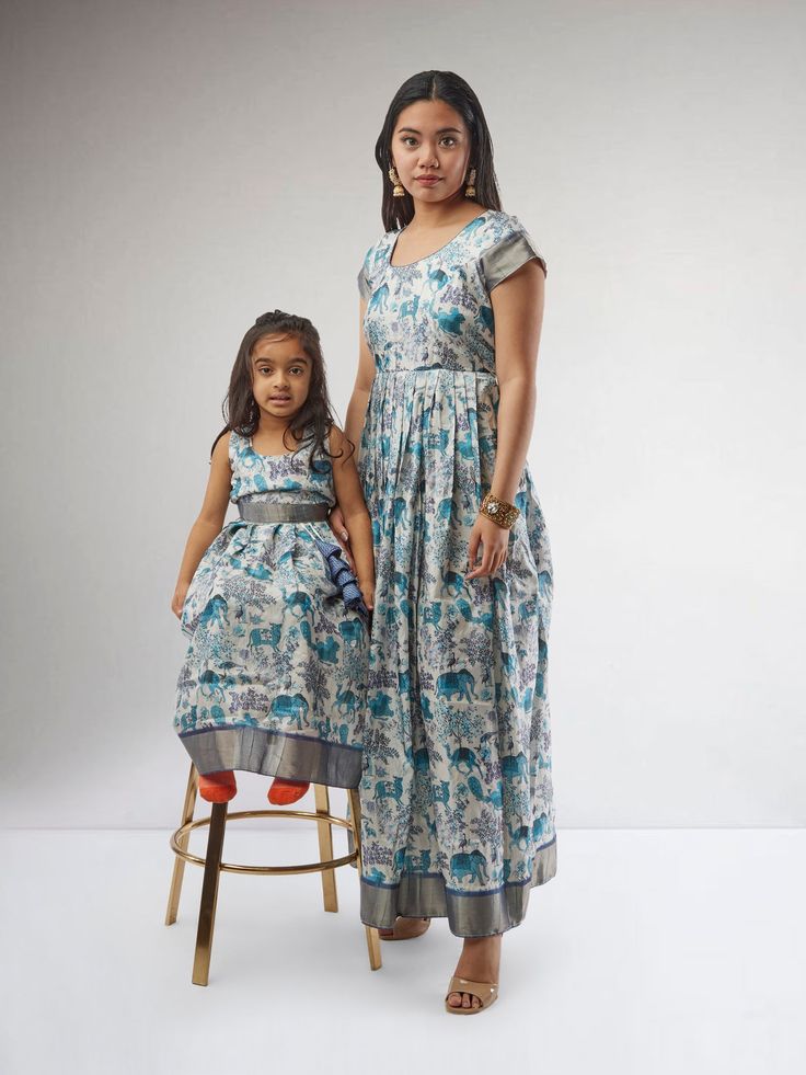 Dress up in style with our Mommy n Me White and Blue Kalankari Print Matching Dresses. These charming outfits feature a beautiful combination of white and blue Kalankari print, perfect for a coordinated look for moms and daughters. The dresses are crafted with care to provide comfort and style, making them ideal for special occasions or casual outings. To keep these dresses looking fresh, we recommend hand washing them in cold water and air drying. Cotton Sleeveless Dress For Navratri, Blue Cotton Maxi Sets, Blue Anarkali Dress For Summer, White Sleeveless Anarkali Dress, Blue Dress For Navratri, Light Blue Festive Maxi Dress, Blue Cotton Wedding Dress, Traditional Light Blue Summer Dress, Festive Light Blue Maxi Dress