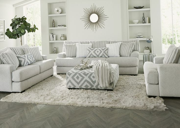 a living room filled with white furniture and lots of pillows on top of a rug