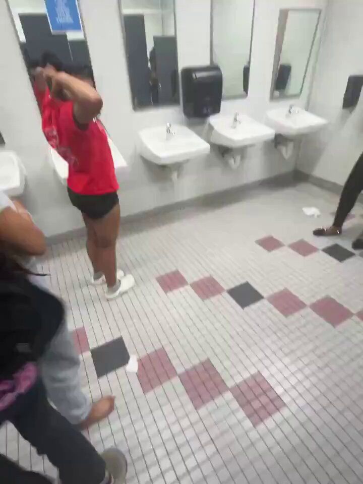 several people in a public bathroom with urinals and sinks