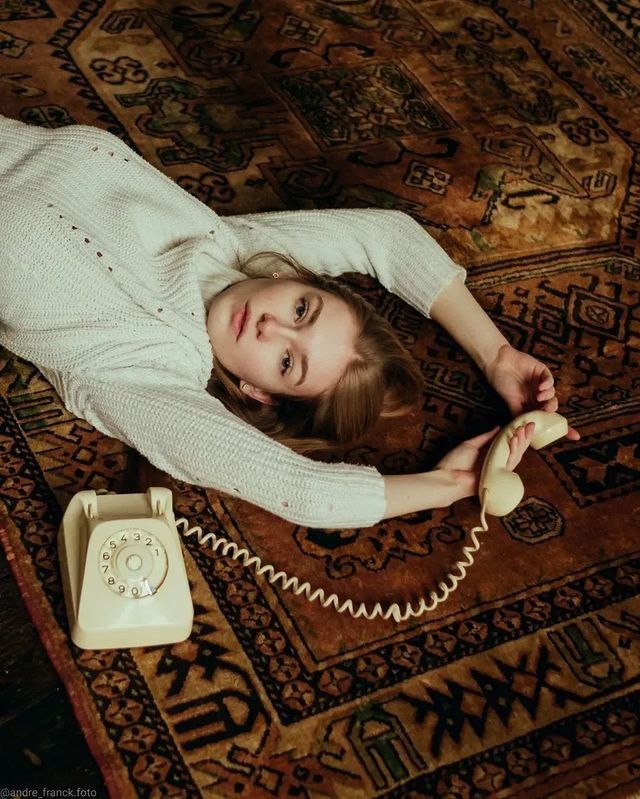 a woman laying on the floor with an old phone