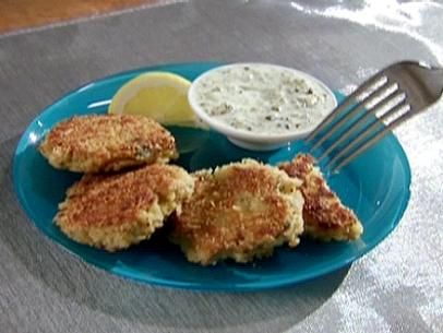 some crab cakes on a blue plate with a side of dipping sauce and lemon wedges