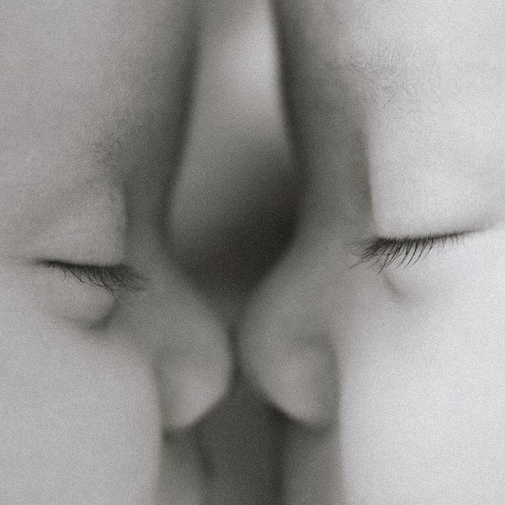 a close up of two people's faces with their noses touching each other and looking at the camera