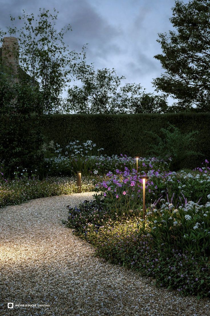 a gravel path in the middle of a garden with purple and white flowers on either side