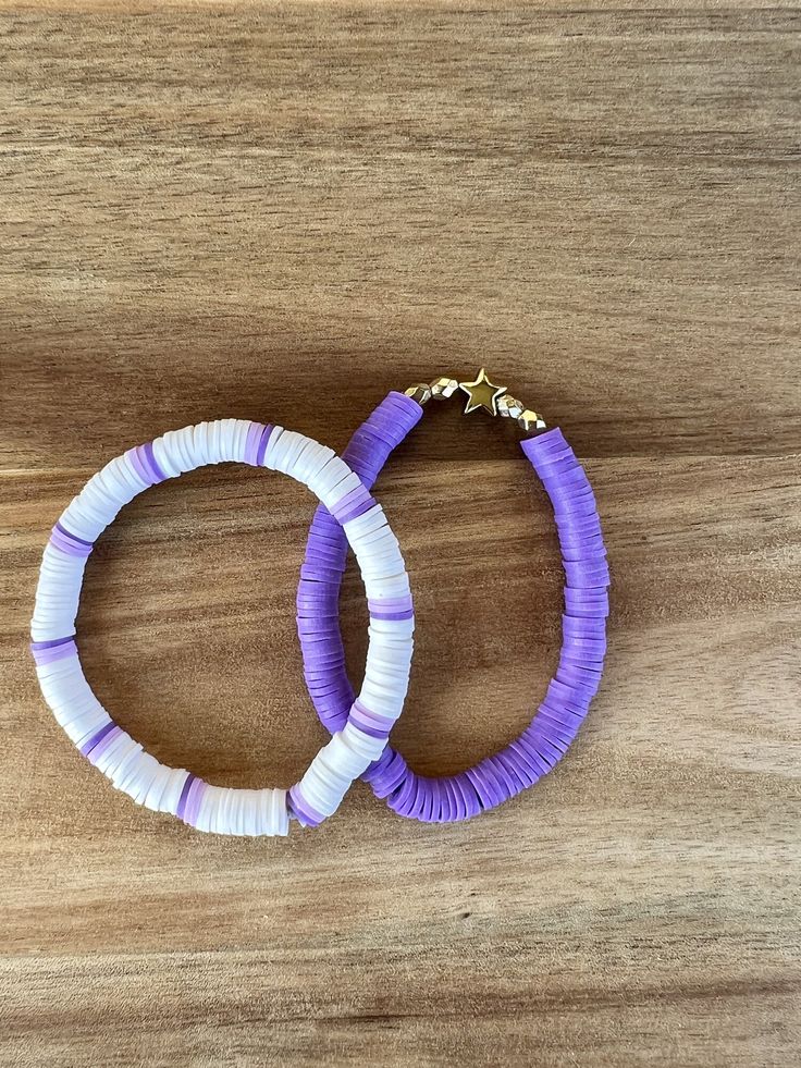 two purple and white bracelets sitting on top of a wooden table