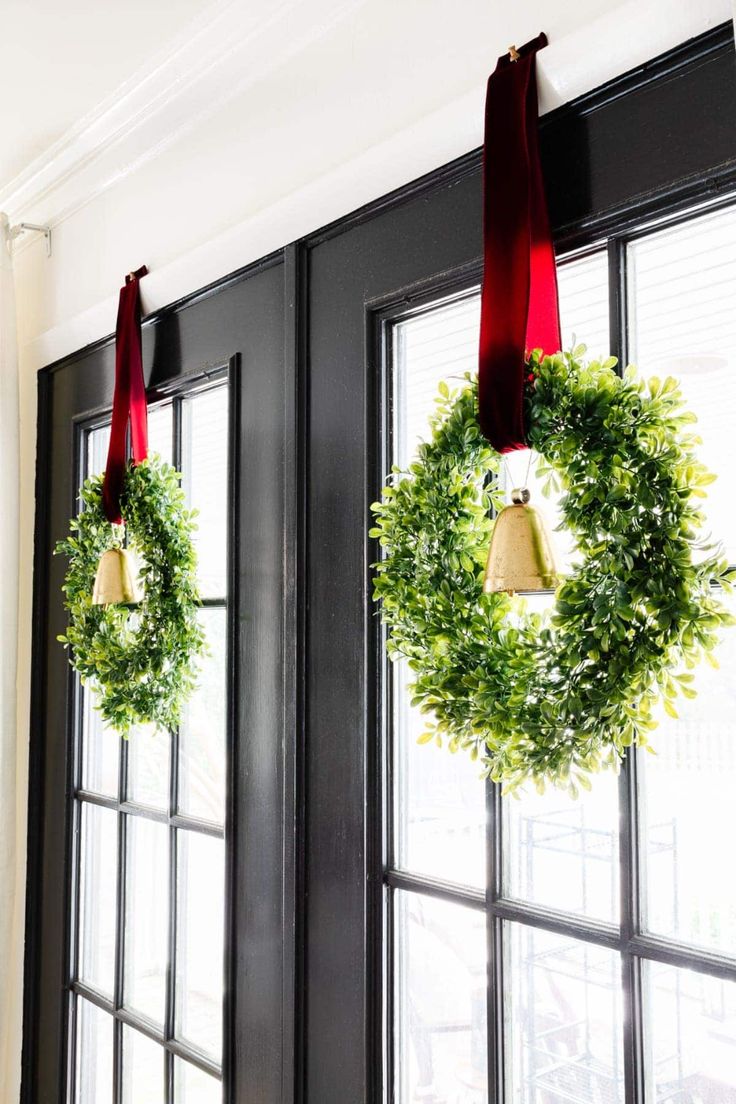 two wreaths hanging from the side of a black door