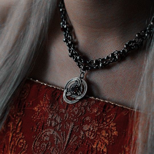 a close up of a person wearing a necklace with a heart pendant on it's chain