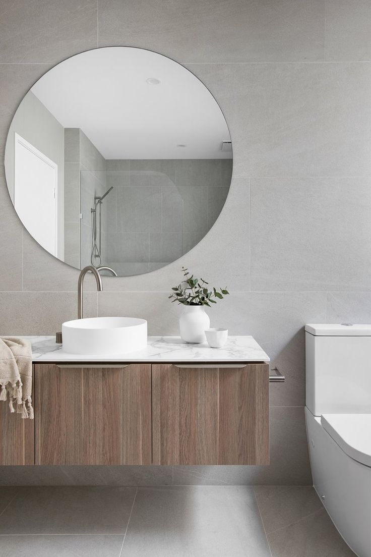 a bathroom with two sinks and a large round mirror