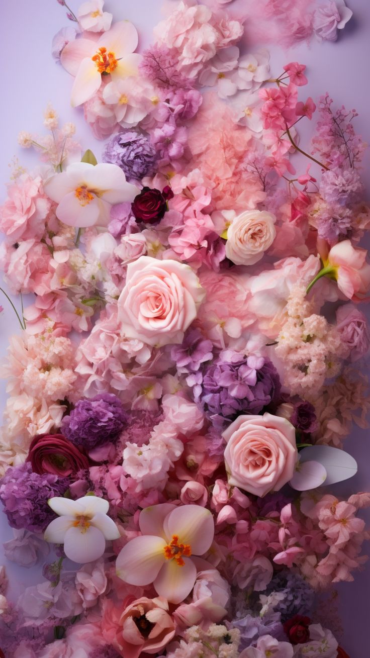 an arrangement of pink and purple flowers on a wall