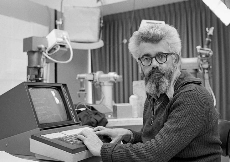 a man sitting at a desk with a computer in front of him on his lap