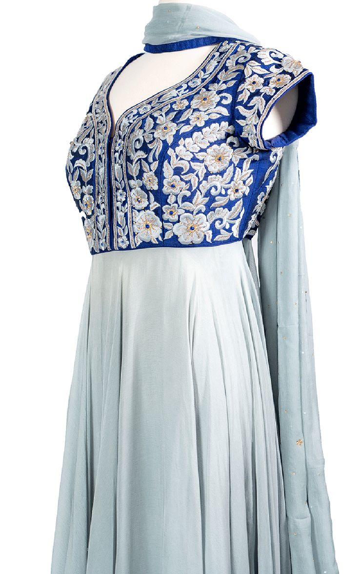 An elegant cool blue chiffon Anarkali drapes beautifully across the body and stands out with a raw silk royal blue top with tonal thread and zari embroidery.Length: 63Fabric: Top - Raw Silk, Gown / Dupatta - ChiffonEmbroidery: Thread, Stone Blue Raw Silk Anarkali Set For Diwali, Blue Anarkali Set With Zari Work For Transitional Season, Transitional Blue Anarkali Set With Zari Work, Elegant Blue Anarkali Set With Cutdana, Blue Georgette Anarkali Set With Cutdana, Blue Georgette Choli For Transitional Season, Silk Churidar With Traditional Drape For Reception, Blue Georgette Anarkali Set With Traditional Drape, Blue Floor-length Traditional Wear For Transitional Season