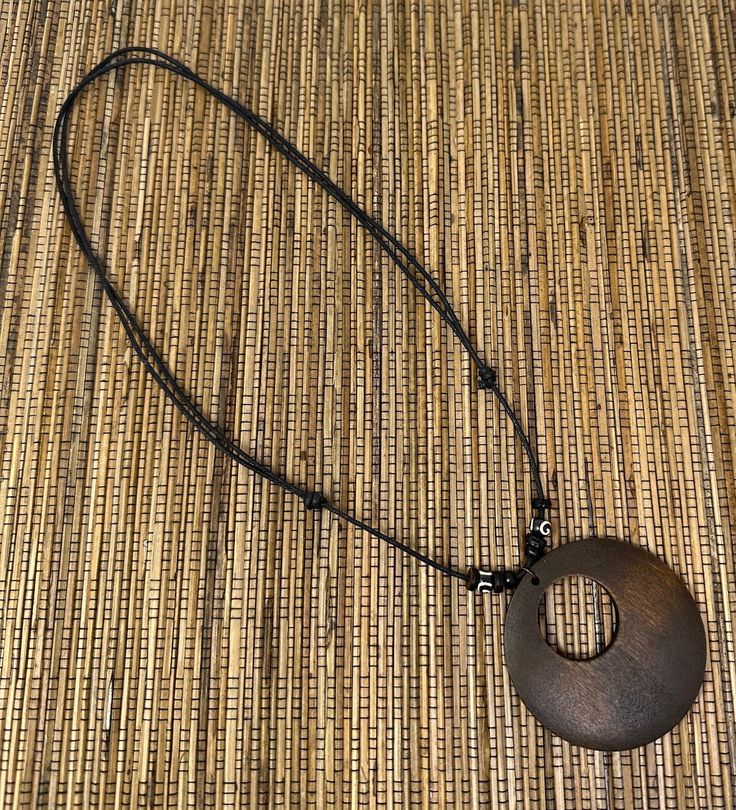 Discover the elegance of nature with our Brown Circle Pendant Necklace, a perfect blend of style and natural beauty. This unisex necklace features a meticulously crafted wooden pendant, showcasing a beautiful wood design that captures the essence of the earth's simplicity and grace. Pendant Specifications:     Size: 2.25 inches in diameter, offering a prominent yet comfortable size.     Material: High-quality wood, chosen for its durability and natural aesthetics. Necklace Features:     Adjustab Adjustable Wood Jewelry Nature-inspired, Adjustable Wood Jewelry In Nature-inspired Style, Adjustable Natural Wood Necklace Nature-inspired, Adjustable Nature-inspired Wooden Jewelry, Adjustable Rustic Necklace With Round Pendant, Adjustable Natural Wood Necklaces, Rustic Adjustable Round Pendant Necklaces, Rustic Natural Wood Necklace, Brown Necklace With Adjustable Cord And Round Pendant