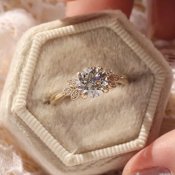 a close up of a person holding an engagement ring in a box with diamonds on it