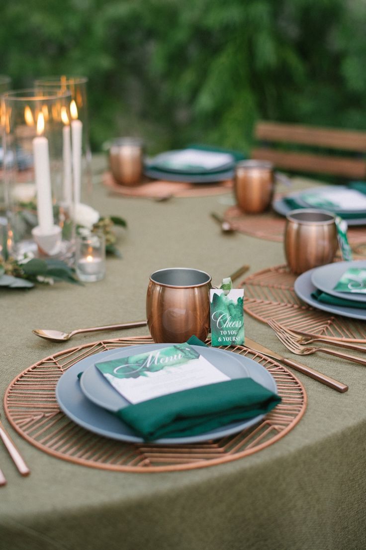 the table is set with green and gold place settings, silverware, napkins, and candles