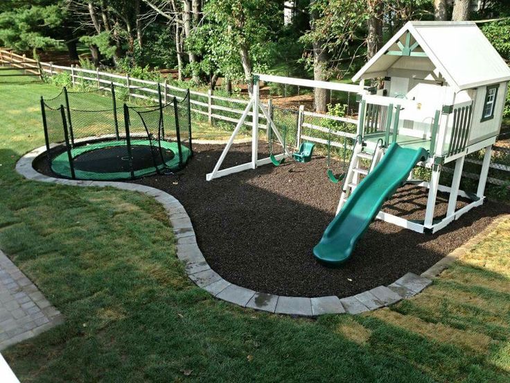 a play area with a slide, swing set and climbing frame in the back yard