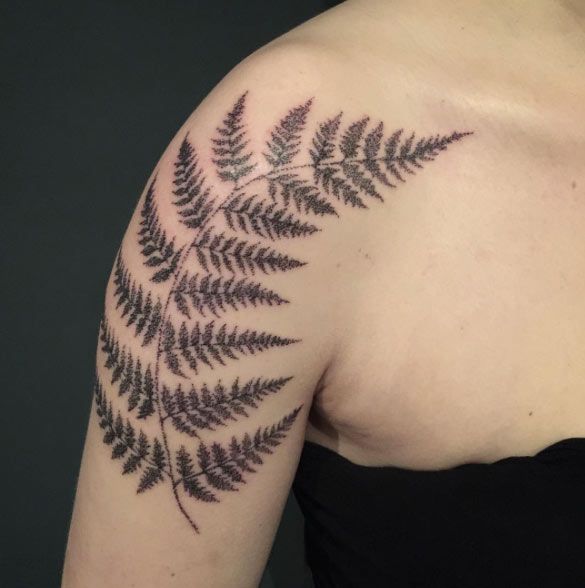 a woman with a tattoo on her arm has a fern leaf design on it's shoulder