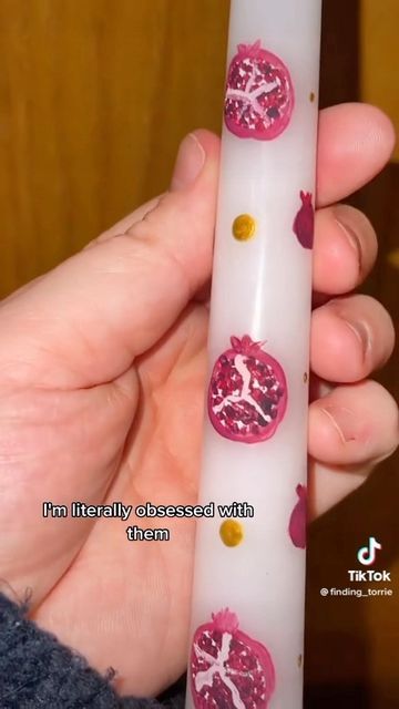 a hand holding a white tube with pink designs on it