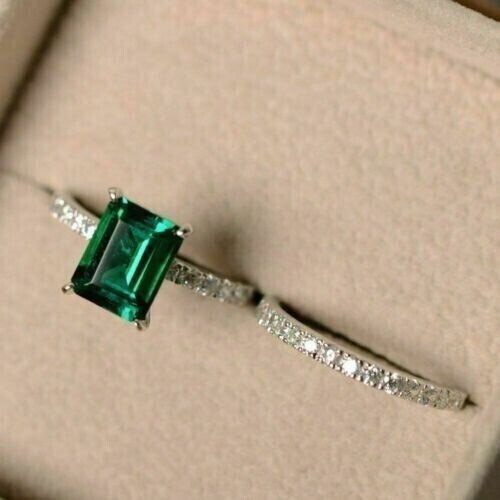 an emerald and diamond ring in a box