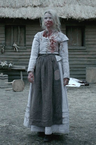 a woman with blood on her face standing in front of a house