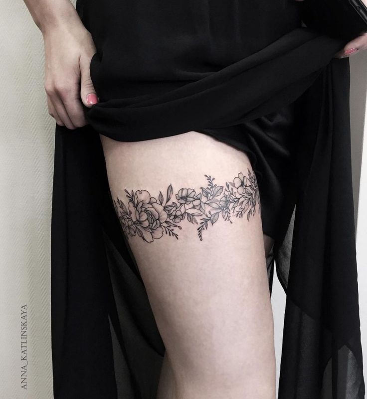 a woman's thigh with flowers and leaves on the bottom part of her leg