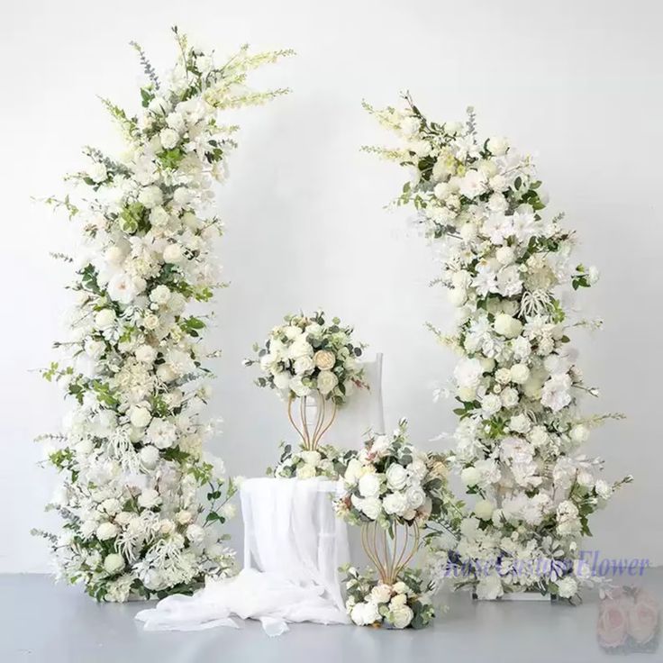 white flowers and greenery are arranged in the shape of an o - shaped arch