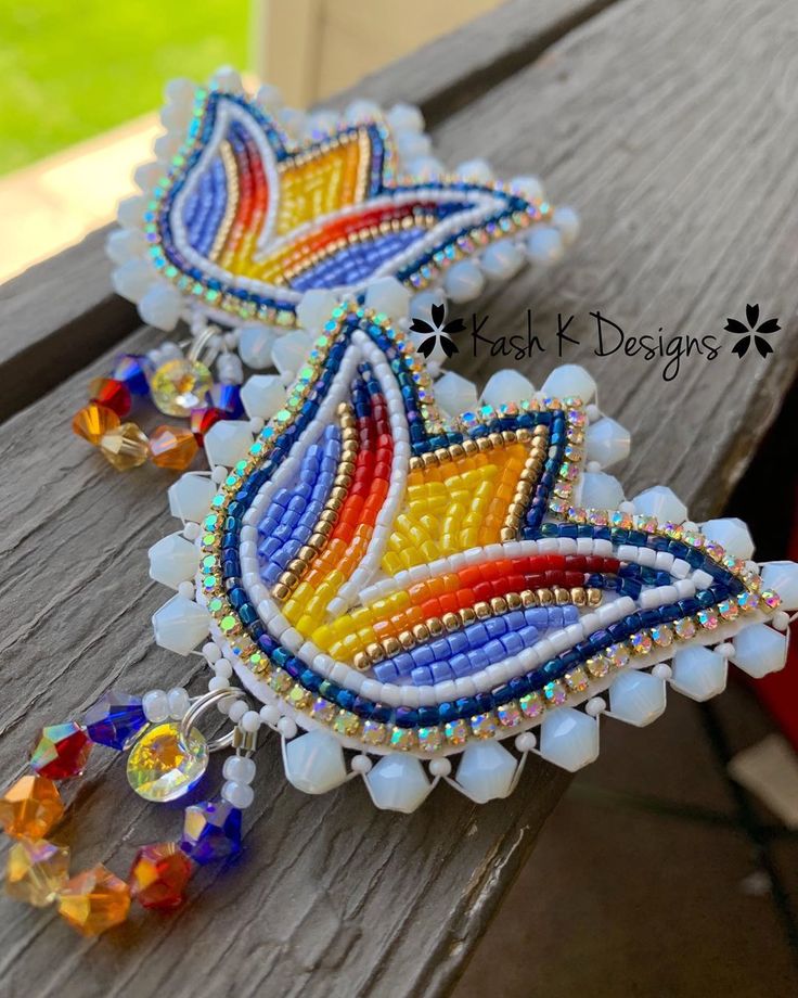 two colorful beaded earrings sitting on top of a wooden bench