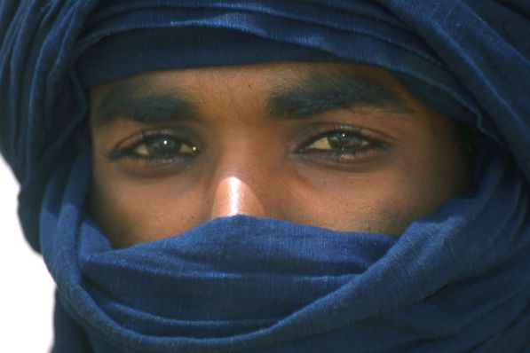 a close up of a person wearing a blue head scarf and looking at the camera