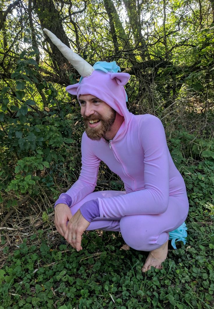 a man in a purple unicorn costume sitting on the ground