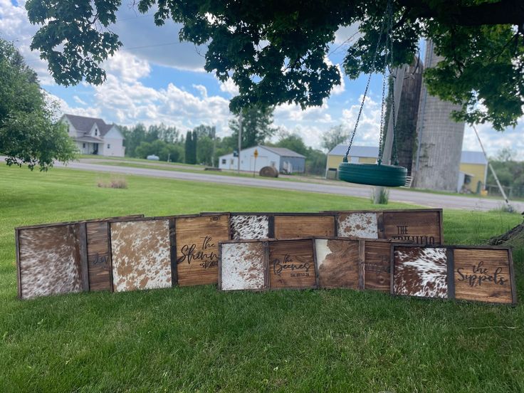 a group of wooden signs sitting on top of a grass covered field next to a tree