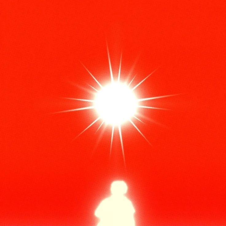 a person standing in front of a bright sun on a red background with the light shining behind them