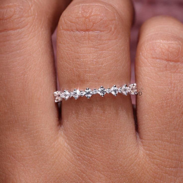 a woman's hand with a wedding band on it, and the ring has five stones